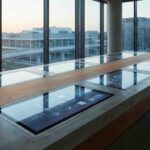 Fotografía editorial de una sala de juntas moderna y vacía con tecnología integrada en materiales físicos como madera y concreto.